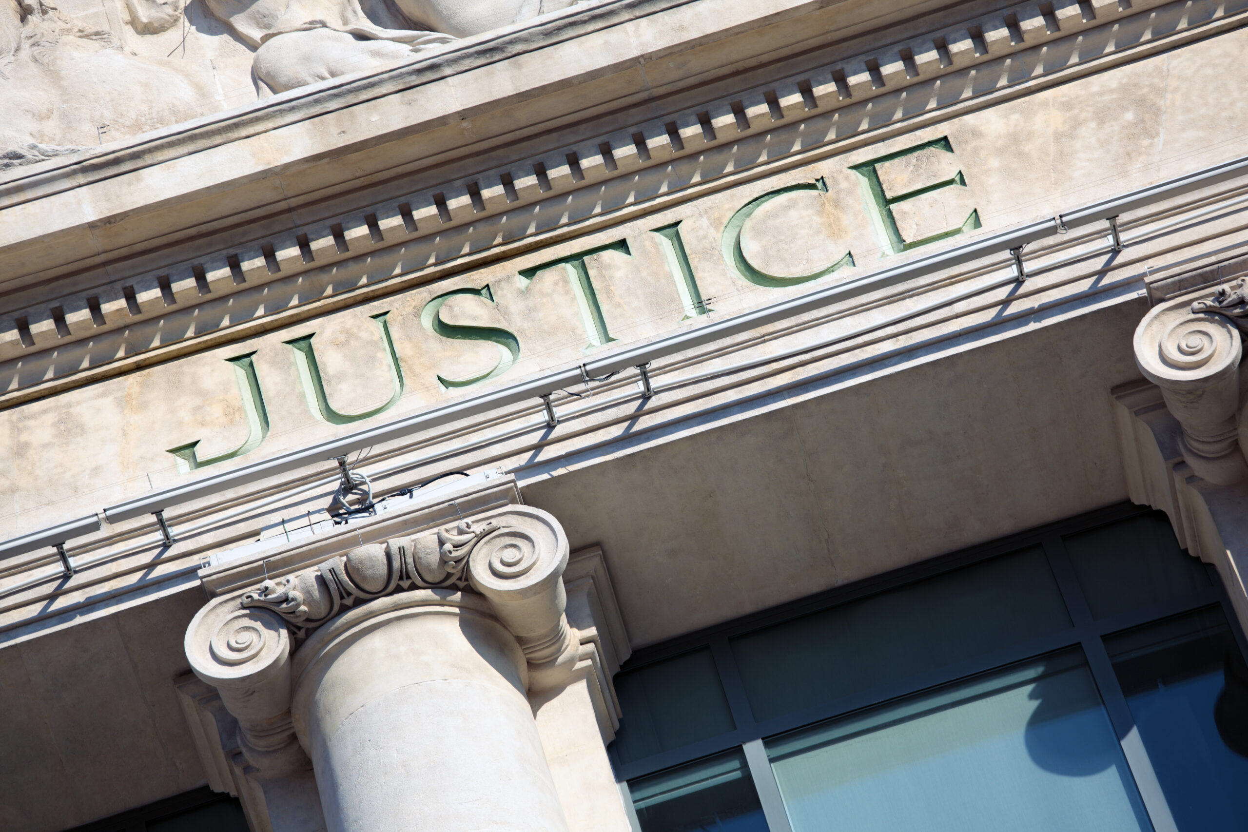 The word Justice on a Courtroom Building.